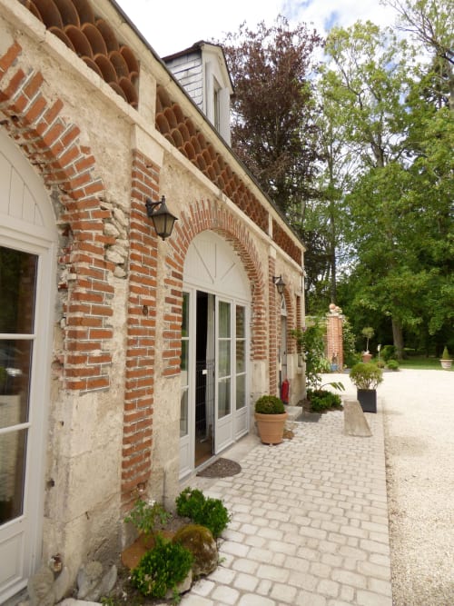 Charming brick and stone courtyard entrance at Les Rives De La Tronne hotel in Mer, France, with potted plants and arched