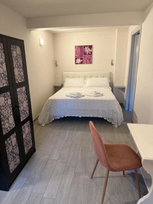 Camera luminosa del B&B di Orvieto con letto matrimoniale, biancheria bianca, opere floreali, pavimenti in legno e arredi moderni