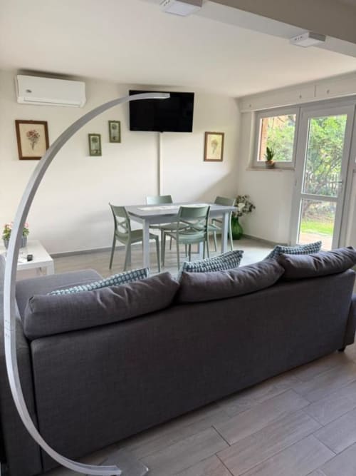 Soggiorno moderno con divano scuro, zona pranzo, TV e vista sul giardino all'Il Giardinetto di Elelú a Orvieto