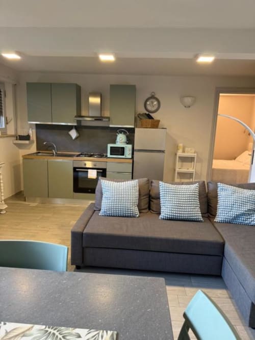 Elegante zona living open-plan con divano grigio e angolo cottura nell'Appartamento Superiore Bilocale di Il Giardinetto di Elelú,