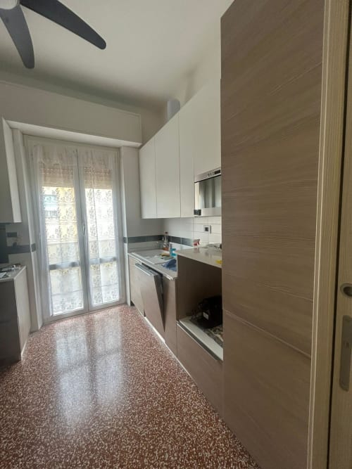 Cucina moderna nell'appartamento Luan House a Genova. Armadiature bianche, accenti marrone, elettrodomestici acciaio inox, terrazzo