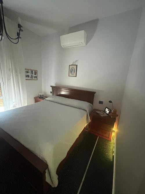 Camera accogliente di Luan House BnB a Genova con letto in legno, biancheria bianca, aria condizionata e servizi moderni