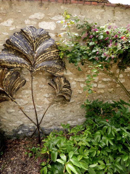 Garden sculpture with metal leaf design against stone wall at Les Rives De La Tronne, Mer France