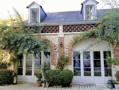 Ivy-covered brick entrance to Les Rives De La Tronne hotel in Mer, France, with blue-roofed dormer windows