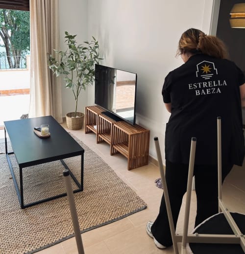 Empleado del hotel Estrella Baeza en Baeza inspeccionando una habitación moderna con mobiliario minimalista e iluminación natural