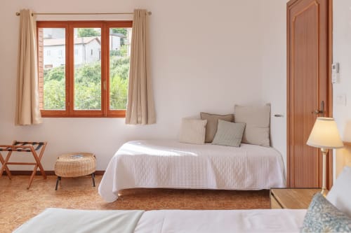 Chambre lumineuse à l'hôtel Allegria à Bajardo avec vue sur les montagnes, cadres de fenêtres en bois et décoration neutre