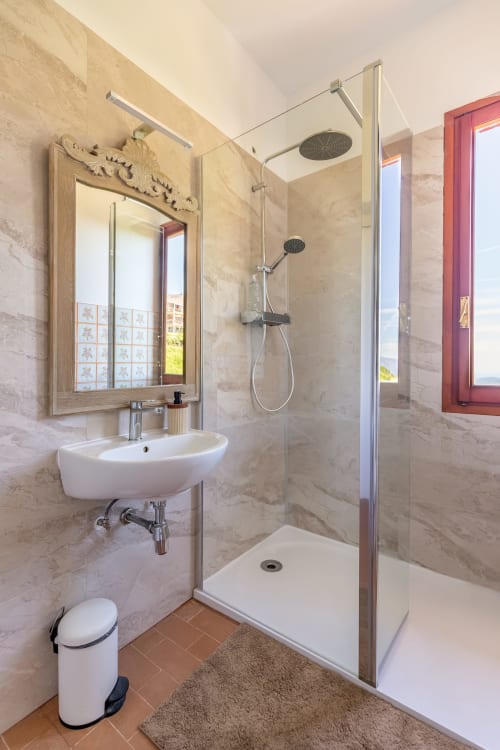 Salle de bain moderne de la Chambre Infinito à l'hôtel Allegria, Bajardo, avec carrelage en marbre, douche à effet pluie et accessoires muraux