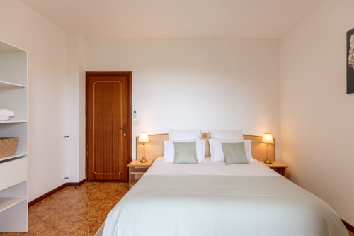 Chambre Infinito de l'hôtel Allegria à Bajardo, Italie. Chambre moderne avec lit queen-size, porte en bois, lampes de chevet, blanc