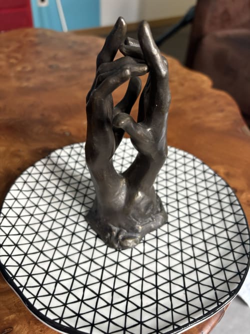Mains sculpturales noires tenant un objet sur un dessous-de-verre aux motifs géométriques, Suite Camille Claudel à Au Richebourg Nogent