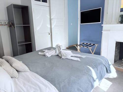 Chambre moderne à l'Au Richebourg Nogent avec mur d'accent bleu, literie grise et TV murale à Nogent-sur-Seine