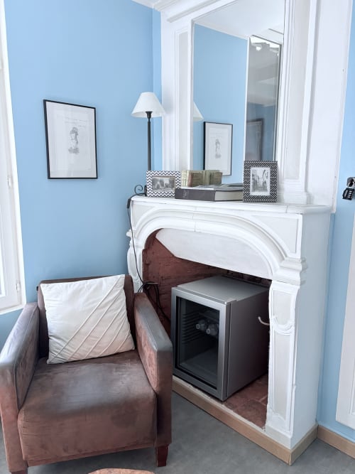 Suite Camille Claudel au Richebourg Nogent : chambre bleue avec cheminée, fauteuil en cuir et miroir