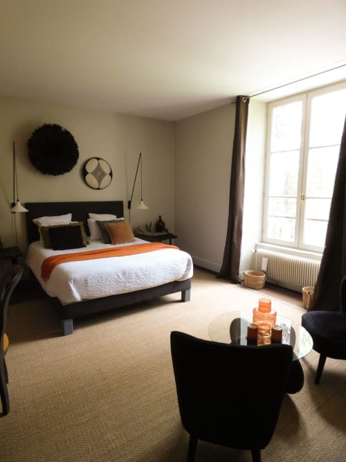 Luxurious bedroom at Les Rives De La Tronne with black bed, orange accents, modern seating area, and large windows