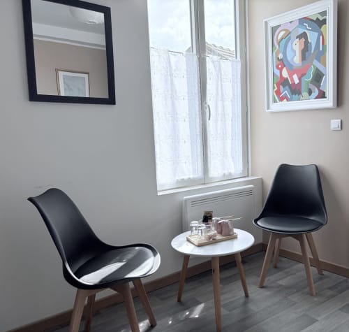 Espace de détente moderne de la Suite Paul Dubois à Au Richebourg Nogent avec chaises noires, table ronde blanche et vue sur le jardin