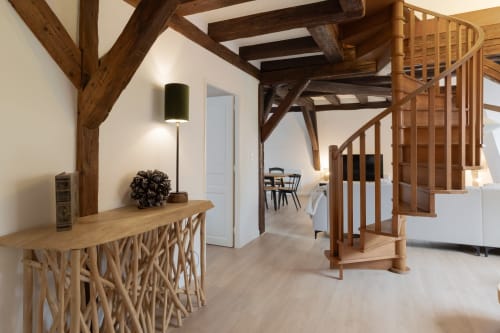 Modern duplex apartment in Colmar with exposed wooden beams, spiral staircase, designer console table, and open living space