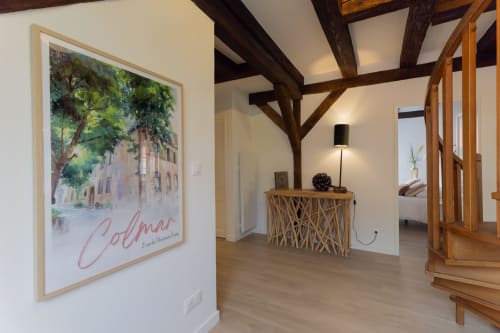 Modern Colmar apartment entryway with exposed wooden beams, framed local landmark art, and designer console table