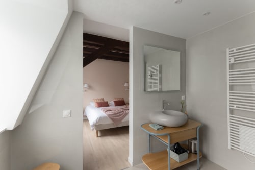 Bathroom view with modern white sink, wooden vanity, and open doorway to bedroom in Le JO·LIE Duplex apartment, Colmar
