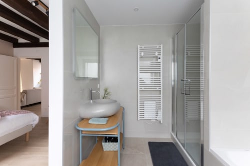 Modern bathroom at Le JO·LIE Duplex in Colmar with round sink, walk-in shower, heated towel rack, and wooden vanity.