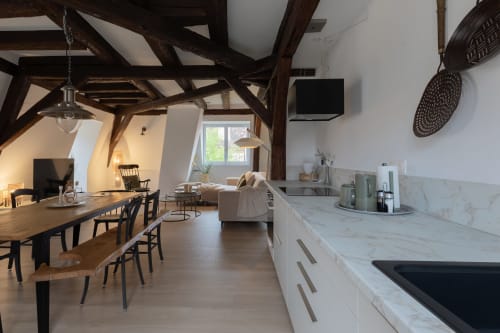 Modern duplex apartment in Colmar with exposed beams, marble kitchen, dining area, and living room with TV