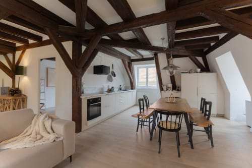 Modern duplex apartment in Colmar with exposed wooden beams, open kitchen, dining area, and comfortable lounge seating