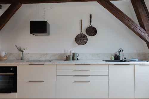 Modern kitchen in Le JO·LIE Duplex, Colmar, with marble countertop, white cabinetry, and decorative cookware