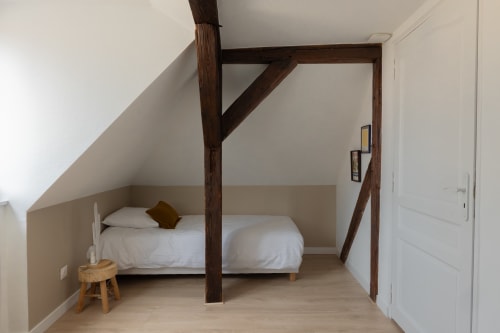 Bedroom with wooden canopy frame, white bedding, and exposed beams at Le JO·LIE Duplex in Colmar