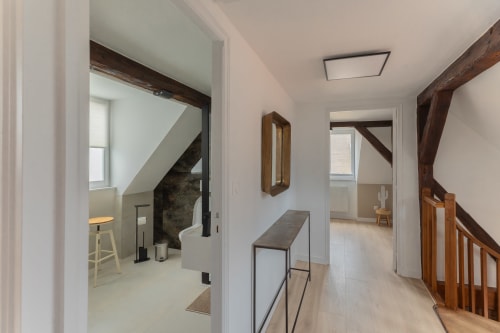 Modern hallway in Le JO·LIE Duplex apartment, Colmar, featuring wooden beams, staircase, and multiple room entrances
