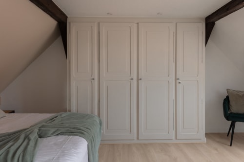 Spacious bedroom in Le JO·LIE Duplex apartment in Colmar with built-in white wardrobes and dark wooden beams