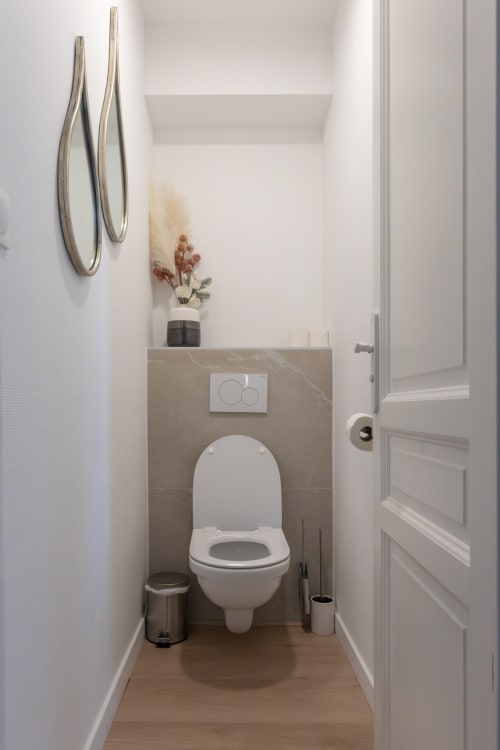 Modern toilet room in Le JO·LIE Duplex apartment, Colmar, with white fixtures and neutral décor