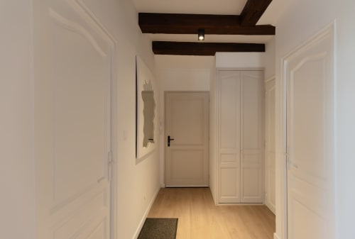 Bright hallway in Le JO·LIE Duplex apartment, Colmar, with wooden beams, cream doors, and wood flooring