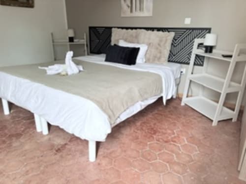 Chambre moderne de l'hôtel Au Richebourg Nogent avec deux lits, têtière noire, mobilier blanc et carrelage en terre cuite