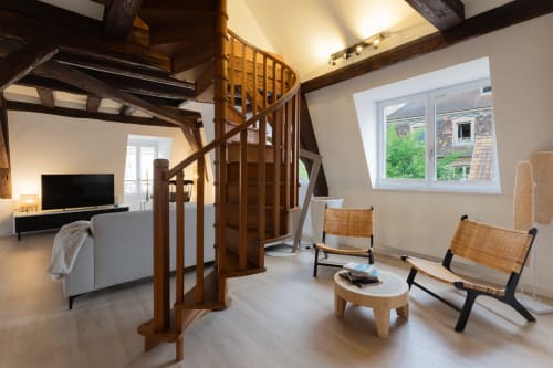 Spacious Colmar duplex loft with spiral staircase, wooden beams, woven chairs and modern amenities.