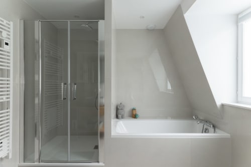 Modern attic bathroom at Le JO·LIE Duplex in Colmar with glass shower and built-in bathtub