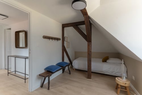 Attic bedroom at Le JO·LIE Duplex in Colmar with wooden beams, single bed, blue bench, and modern lighting.