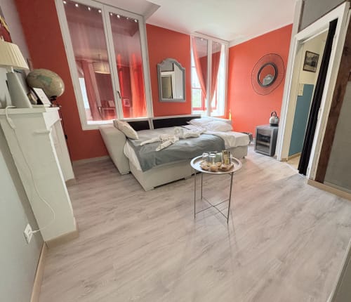 Suite spacieuse Joseph Marius Ramus à Au Richebourg Nogent avec canapé-lit beige, murs corail et vue sur le jardin