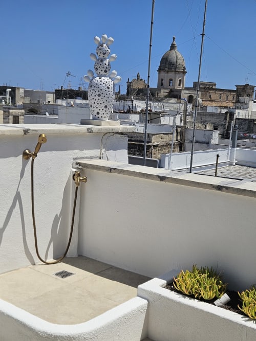 Rooftop terrace at Pura Vita Apartments, Monopoli, with white lounge area, brass fixtures, and coastal town views