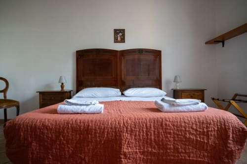 Spaziosa camera da letto presso Casa di Alfredo B&B a Siena con testiera in legno, coperta rossa, cuscini e asciugamani bianchi