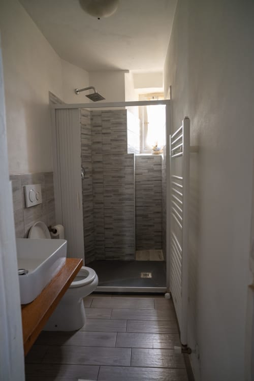 Bagno moderno in Casa di Alfredo bed & breakfast, Siena, con cabina doccia, toilet e lavandino con piano in legno