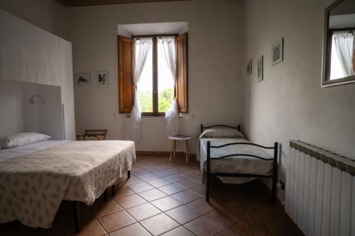 Luminosa camera tripla a Casa di Alfredo B&B a Siena con due letti, pavimenti in cotto e vista sulle colline toscane