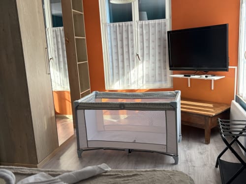 Suite orange éclatante à l'Au Richebourg Nogent avec lit parapluie, télévision et fenêtres avec vue sur le jardin