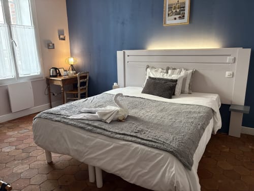 Suite Gustave Flaubert à l'Au Richebourg Nogent : chambre avec lit blanc, mur bleu et vue sur la ville