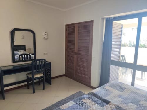 Quarto luminoso com camas twin, penteadeira, guarda-roupa em madeira e acesso a terraço com vista para o jardim na Albufeira Inn