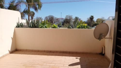 Terraço ensolarado da Albufeira Inn com piso em azulejos, paredes bege, plantas em vasos e vistas da cidade em Albufeira, Portugal