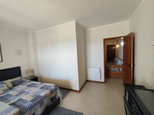 Quarto espaçoso na Albufeira Inn com cama de padrão azul, guarda-roupa e piso azuleijado