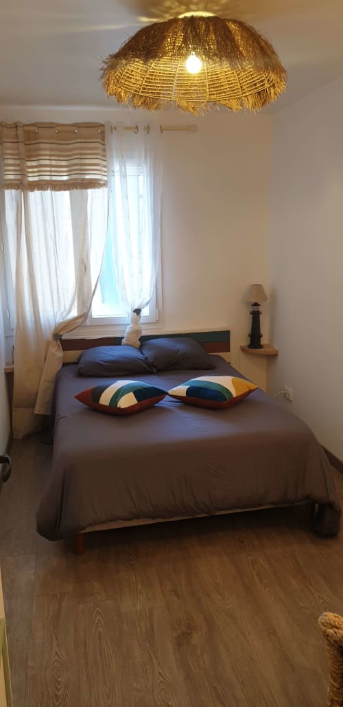 Chambre L'espiguette à l'hôtel Vesta Gaia à Saint-Gilles : lit marron, oreillers rayés, suspension dorée et jardin