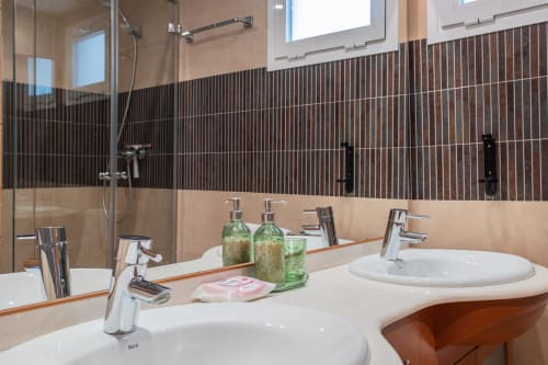 Baño moderno en Haus Holiday Homes, San Pedro del Pinatar, con doble lavamanos, grifería cromada y azulejos a rayas oscuras