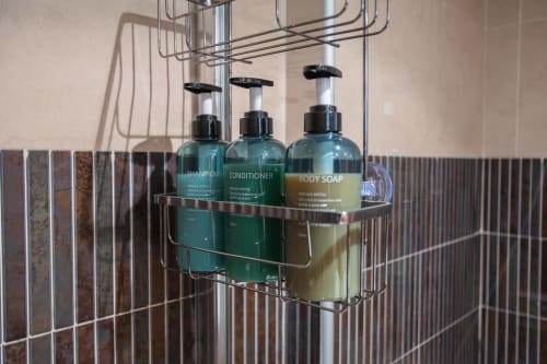 Estante cromado en baño de apartamento con botellas de champú, acondicionador y jabón corporal