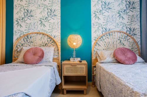 Dos camas con cabeceros tejidos, almohadas rosas y papel tapiz botánico en apartamento Haus Holiday Homes, San Pedro del Pinatar