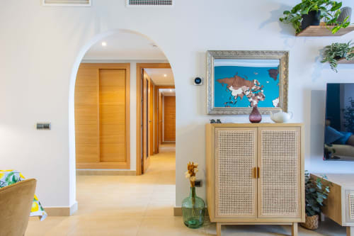 Pasillo moderno con puerta arqueada, puertas de madera, mapa enmarcado, plantas en maceta y mueble decorativo en Haus Holiday