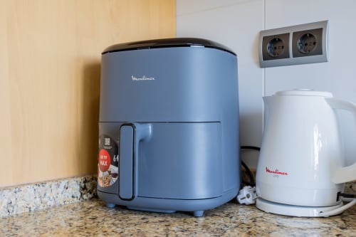 Freidora de aire azul Moulinex y hervidor blanco Moulinex sobre encimera de granito en la cocina del apartamento de Haus Holiday Homes, San Pedro