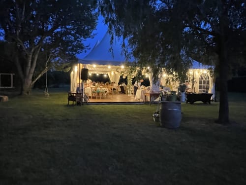 Tente de réception en soirée aux Jardins Du Soleil, Avignon - salle à manger en plein air illuminée sous les arbres au crépuscule